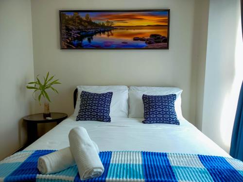 长滩岛L'eau Bleue Boracay Condotel的一张带蓝色和白色枕头的床和绘画