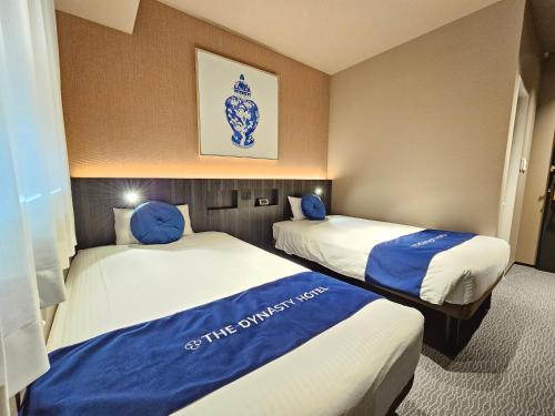 大阪Dynasty Hotel & Resort Osaka的两张位于酒店客房的床,配有蓝色枕头
