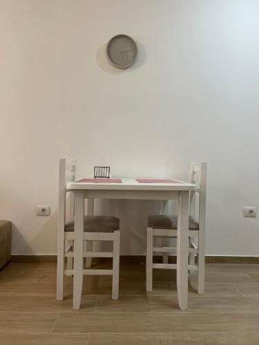 地拉那Gex apartments的一张带两把椅子的白色桌子和墙上的时钟