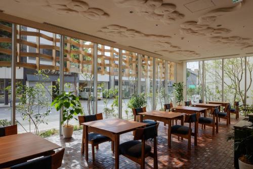 出云市Hotel Kararako的餐厅设有木桌、椅子和窗户。