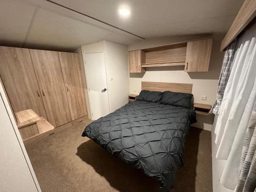 Great BillingBilling Aquadrome Luxury Static Caravan的一间带一张床和木制橱柜的小卧室