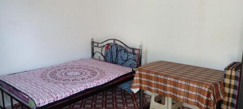 PernemMendonca's Home Stay的一间设有一张床和一张桌子及毯子的房间