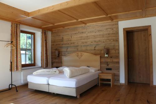 阿亨基希Gasthaus Marie的卧室设有白色的床和木墙
