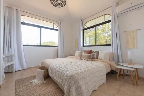 苏莎亚Flat Anchor Marine Monte Vista的白色卧室设有一张大床和两个窗户