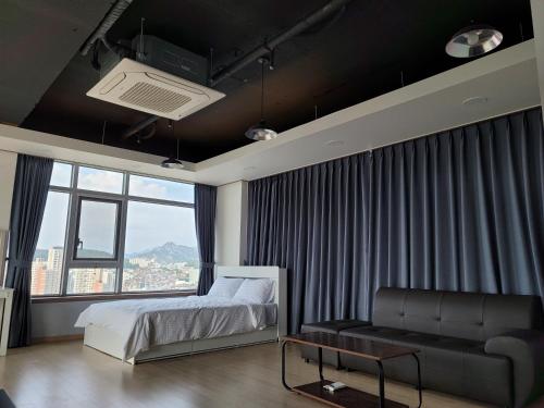 首尔YD公寓酒店的一间卧室配有一张床、一张沙发和一个窗口
