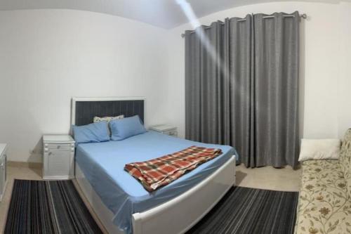 New cairoAppartment in New Cairo Madinaty的一间卧室配有蓝色的床和黑色窗帘