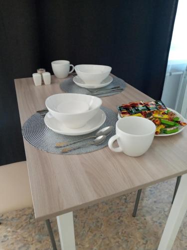 乌斯季卡缅诺戈尔斯克Уютная студия на Ауэзова 3的木桌,上面放着碗和盘子