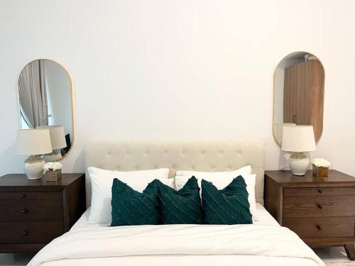 Al QurayyahClassy Studio in Masdar City的一间卧室配有一张带绿色枕头的床和两面镜子