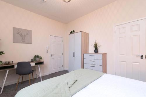 德比cheerful double en-suite with free wifi的一间卧室配有一张床、一张桌子和一把椅子