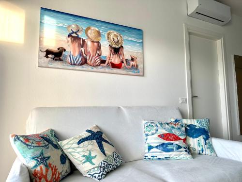 利尼亚诺萨比亚多罗Beach Front Apartment Sabbiadoro的墙上的画,上面是白色沙发,上面有枕头