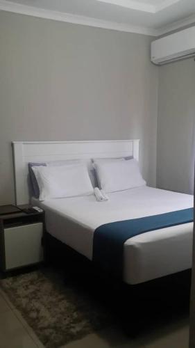 卡萨内Chobe Blue Guest Inn的一间卧室配有一张白色的床和蓝色的毯子