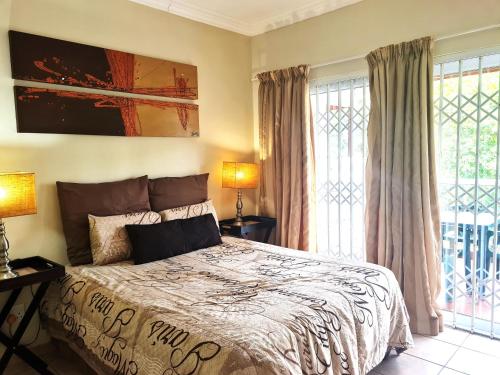 谢丽海滩Kingfisher E的一间卧室配有一张带两盏灯和窗户的床。