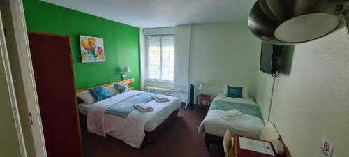 La ChâtaigneraieLe 120 - Groupe Logis Hotels - Ex Auberge la Terrasse的一间卧室设有两张床和绿色的墙壁