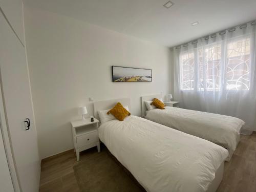 马德里ALOJAMIENTO TURISTICO LAS VISTILLAS MADRID RIO的白色客房的两张床,设有窗户