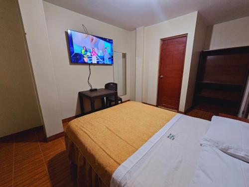 纳斯卡HOSTAL VEGA'S NAZCA的酒店客房设有一张床和墙上的电视