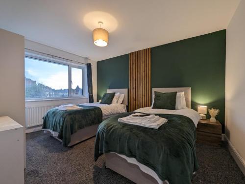 切森特Oakwood Suite - Sleeps 5 - Contractors - Smart TVs in all rooms的一间卧室设有两张带绿色墙壁和窗户的床。