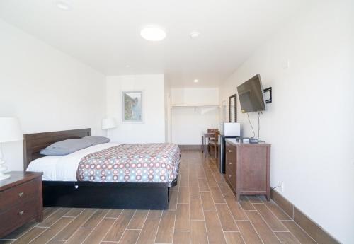 长滩SIGNAL HILL MOTEL BEACH MOTEL的一间卧室配有一张床和一台平面电视