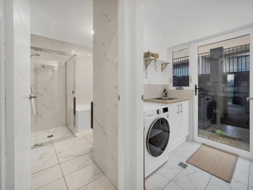 金德拜恩Alloura 2的白色的浴室设有洗衣机和淋浴。