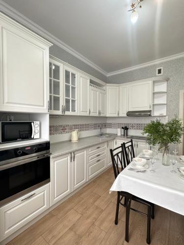 塔尔迪科尔Однокомнатные апартаменты на Экспо的厨房配有白色橱柜和桌椅