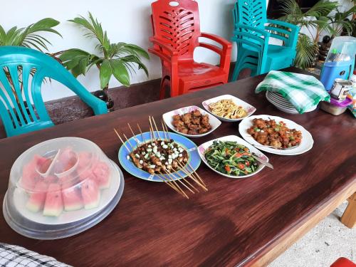 RiungRiung Tiga Empat Tujuh Guesthouse的一张木桌,上面放着食物盘