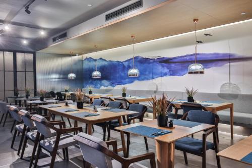 杭州杭州西湖武林Pagoda君亭设计酒店的餐厅设有木桌和椅子,墙上挂有绘画作品