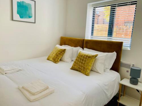 格洛斯特Ten - Central Apartment - Contractors Professionals的一张带白色床单和枕头的床以及窗户