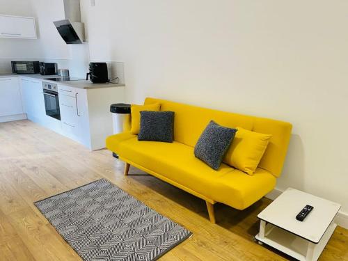 格洛斯特Ten - Central Apartment - Contractors Professionals的客厅设有一张黄色沙发,配有厨房