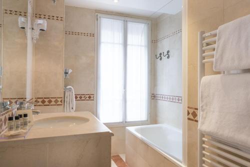 巴黎槐树之星酒店的一间带水槽和浴缸的浴室以及窗户。