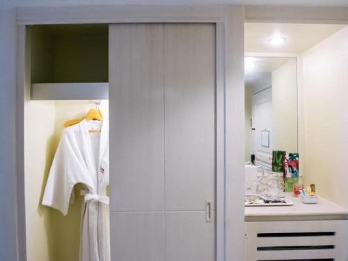 曼谷帕拉左酒店的配有白色浴袍和淋浴的浴室