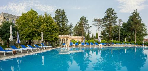 茨卡尔图博Legends Tskaltubo Spa Resort的一个带蓝色椅子和树木的大型游泳池