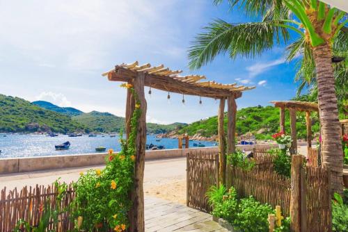 永熙La Mer - Vĩnh Hy bay - beachfront villa CHÀI的棕榈树海滩上的木拱门