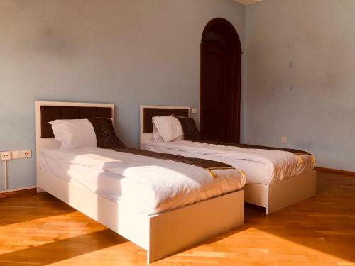 巴库ART inn hotel的配有白色墙壁和木地板的客房内的两张床