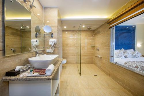 斯利那加ARCO Hotels and Resorts Srinagar的一间带水槽和淋浴的浴室以及一张床