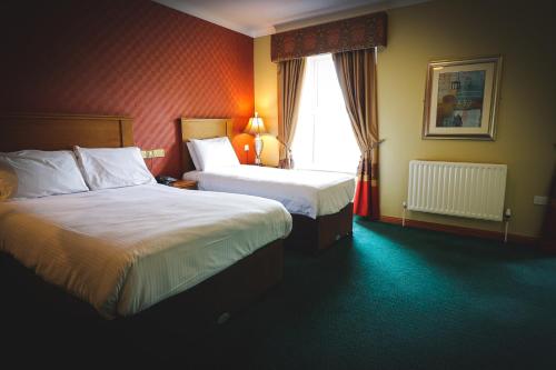 ToomeO'Neill Arms Hotel的酒店客房设有两张床和窗户。