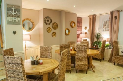 滕比The Belgrave Hotel Tenby的一间带木桌和椅子的用餐室