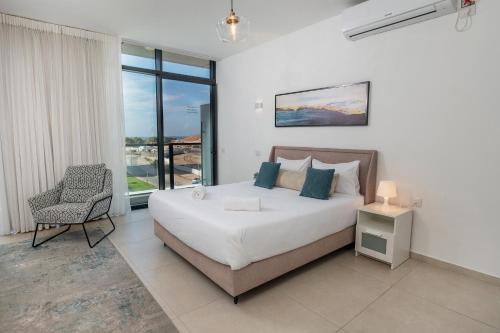 巴特亚姆Hi-Yam SeaView Apartments & Suites - יש ממ"ד的卧室配有床、椅子和窗户。