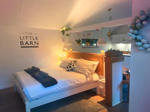 HoxneThe Little Barn的卧室配有白色床,墙上有标志
