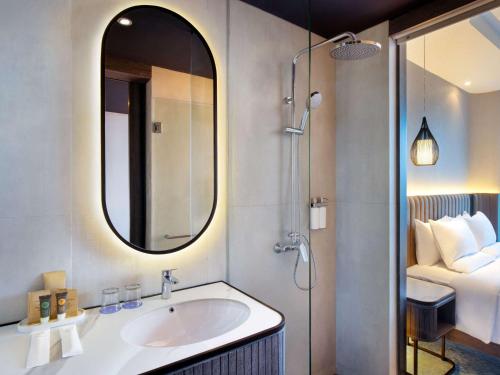 日惹Novotel Yogyakarta International Airport Kulon Progo的一间带水槽和镜子的浴室以及一张床