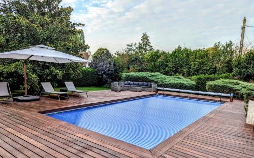巴比松Villa Barbizon的木制甲板上的游泳池,配有遮阳伞