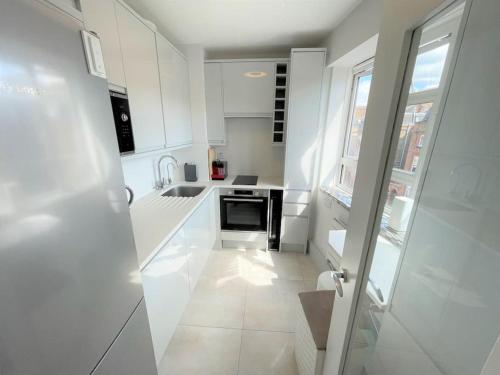 伦敦Large South Facing Studio Flat的白色的厨房配有白色橱柜和窗户