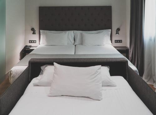 马德里泽尼特阿贝巴酒店的一间卧室配有两张带白色床单和枕头的床。