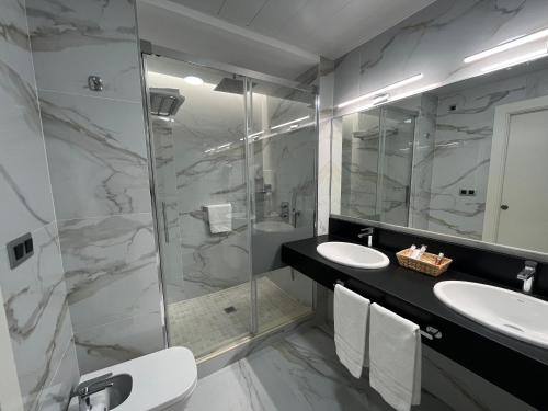 卢塞纳卢塞纳圣多明各酒店的一间带两个水槽和玻璃淋浴间的浴室