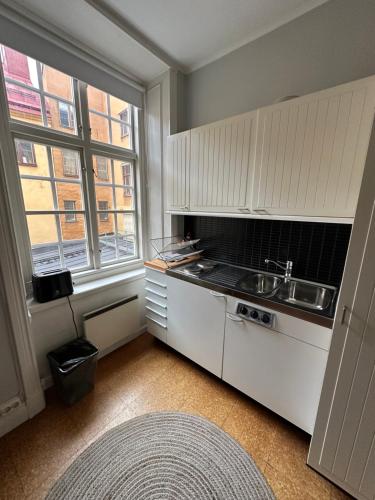 斯德哥尔摩Gamla Stan的厨房配有白色橱柜、水槽和窗户。