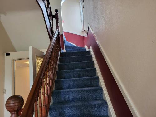 特伦特河畔斯托克Victoria Guest House的蓝色地毯的建筑里,有一段楼梯