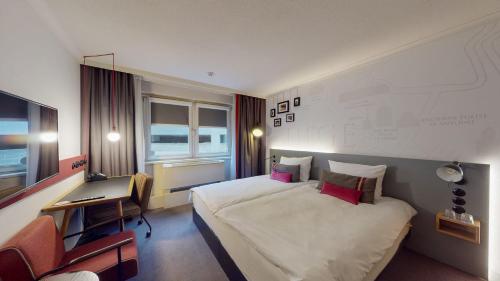 列日pentahotel Liège的酒店客房设有一张大床和一张书桌。
