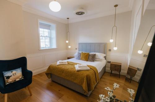 里士满WENSLEYDALE, OLD SCHOOL ROOMS - Ground Floor Luxury Apartment in Richmond, North Yorkshire的一间卧室配有一张床和一把椅子