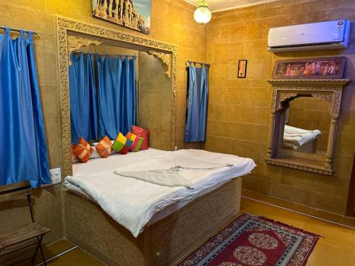 斋沙默尔Hotel Pol Haveli Jaisalmer的一张位于带镜子和蓝色窗帘的房间的床铺