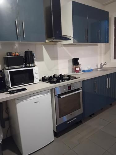 圣但尼une maison en ville的厨房配有蓝色橱柜和炉灶烤箱。
