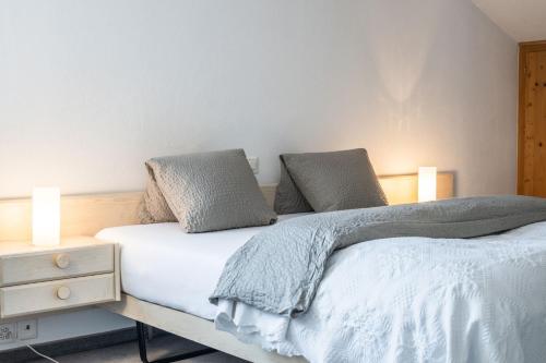 Schiers阿尔皮纳酒店的一间卧室配有带两个枕头的床和床头柜