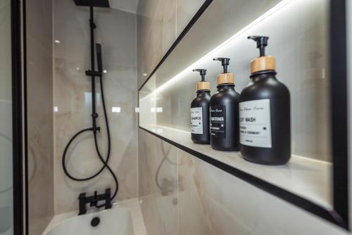 曼彻斯特Exquisite 6 Bedroom Luxury Home Manchester的浴室内置在架子上的三个黑瓶子
